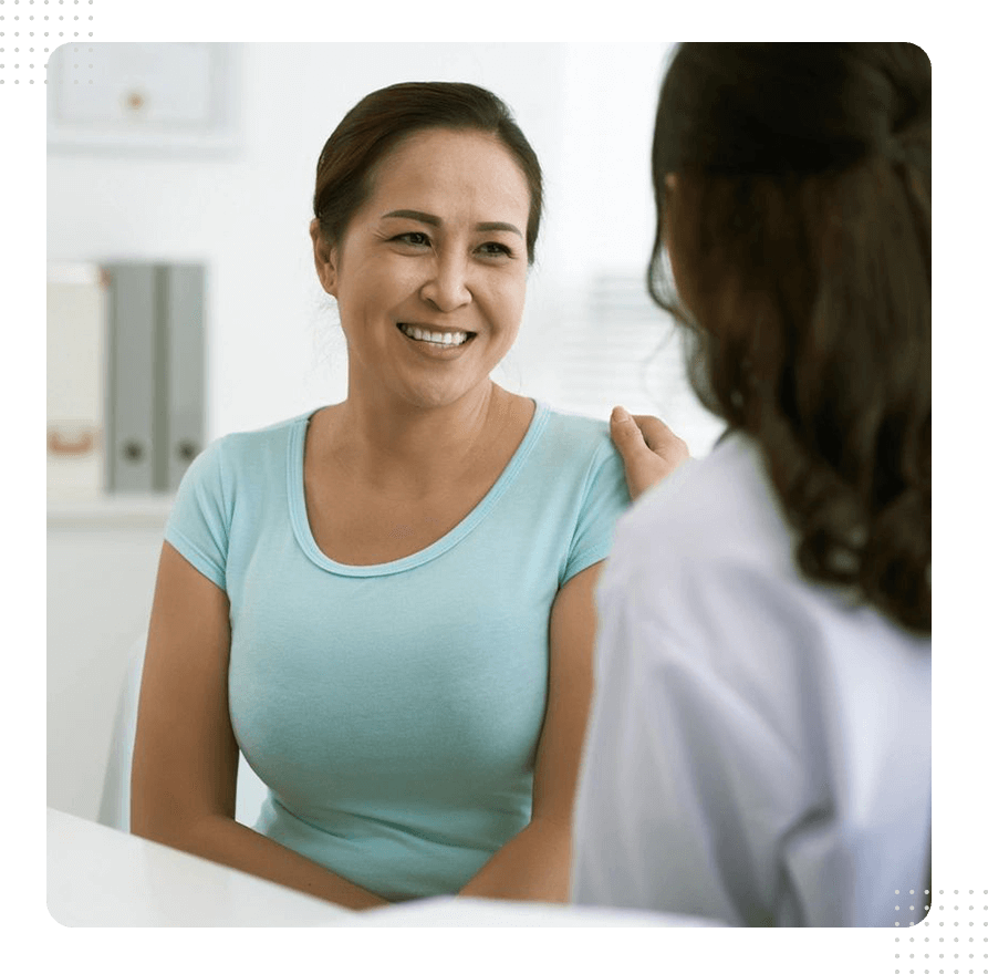 A woman smiles at the camera while talking to another person.