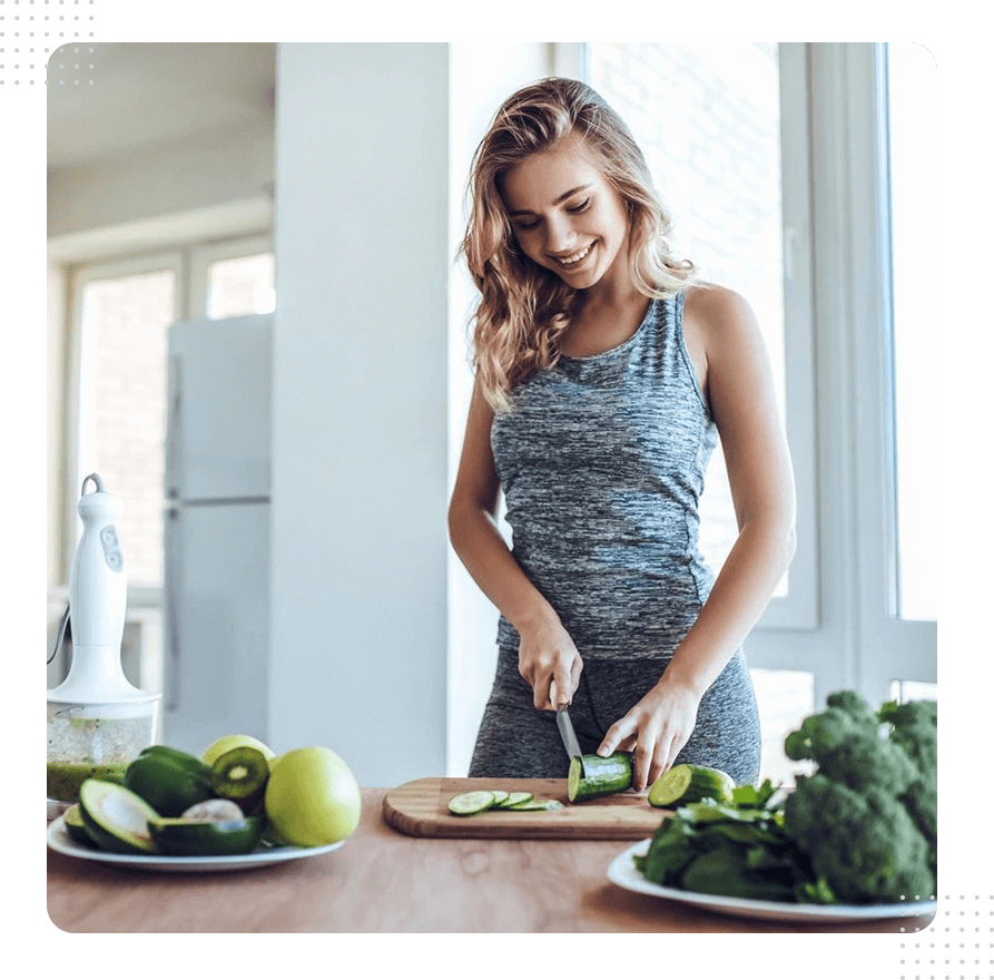 A woman cutting up vegetables on top of a wooden table.